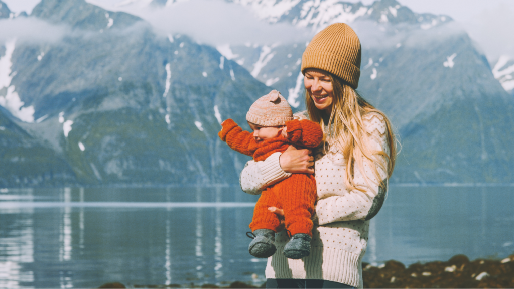 Forsikre det som er viktig i livet; Mor holder baby med vakker fjellnatur i bakgrunnen.